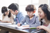 Asian parents helping children with homework — Stock Photo