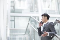Chinese businessman talking on phone in office building — Stock Photo