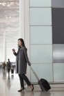 Asiática mujer tirando de equipaje en aeropuerto lobby - foto de stock