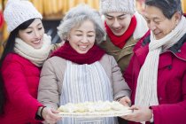 Chinese family standing with traditional dumplings — Stock Photo