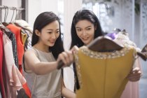 Chinese female friends looking at dress in clothing store — Stock Photo