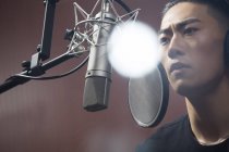 Hombre chino cantando en estudio de grabación - foto de stock