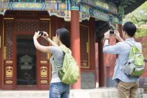 Pareja china tomando fotos con smartphones en Lama Temple - foto de stock