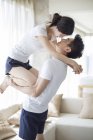 Chinese man carrying woman face to face at home — Stock Photo