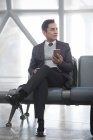 Asiatico uomo holding smartphone in aeroporto — Foto stock