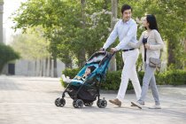 Asiática pareja caminando en parque con bebé chica - foto de stock