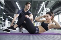 Asiatico donna working con trainer a gym — Foto stock