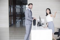 Businessman talking with receptionist in office building — Stock Photo
