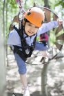 Chinese girl in tree top adventure park wooden tube — Stock Photo