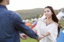 Happy chinese couple holding hands at music festival lawn — Stock Photo