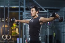 Hombre chino levantando pesas en el gimnasio - foto de stock