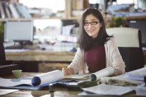 Architetto donna seduta a tavola in ufficio e sorridente — Foto stock
