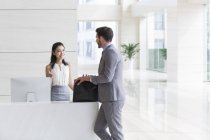 Businessman talking with receptionist in office building — Stock Photo
