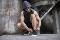 Uomo atleta cinese allacciatura scarpe pizzo — Foto stock