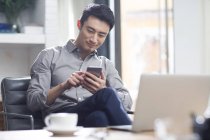 Азиатский мужчина с помощью смартфона в офисе — стоковое фото