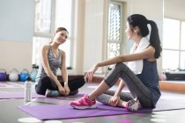Asian women resting on mats at gym — Stock Photo
