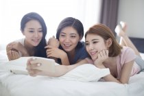 Женщины-подруги делают селфи на кровати — стоковое фото