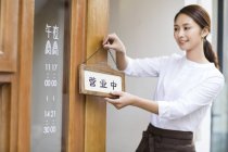 Chinese waitress hanging open sign on restaurant door — Stock Photo