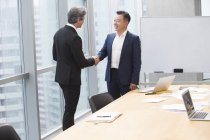 Uomini d'affari che si stringono la mano in sala riunioni — Foto stock