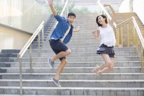 Chinese couple jumping on street steps — Stock Photo