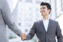 Chinese businessmen shaking hands on street — Stock Photo