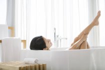 Chinese woman taking bath with legs raised — Stock Photo