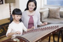 Chinese mother teaching daughter traditional musical instrument zither — Stock Photo