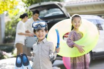 Chinesische Geschwister mit Wassersportausrüstung posieren vor Auto und Eltern — Stockfoto