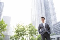 Uomo d'affari cinese in piedi sulla strada e guardando in macchina fotografica — Foto stock