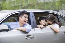 Familia china montando en coche y riendo - foto de stock