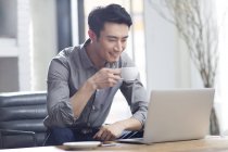 Hombre asiático trabajando con portátil en la oficina - foto de stock