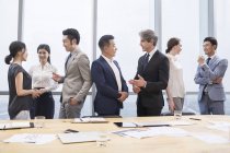 Equipo empresarial chino que se reúne con socios extranjeros en la sala de juntas - foto de stock