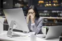 Tired chinese businesswoman working late in office — Stock Photo