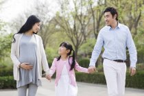 Азиатская семья держалась за руки во время прогулки в парке — стоковое фото