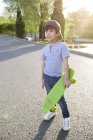 Chinese boy posing with skateboard on road — Stock Photo