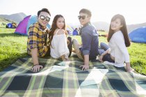 Amigos chineses sentados em cobertor no festival de música — Fotografia de Stock