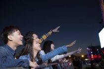 Amigos chinos viendo conciertos y cantando en el festival de música - foto de stock