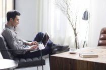 Hombre asiático trabajando con portátil en la oficina - foto de stock