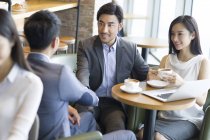 Asian business people shaking hands while meeting in cafe — Stock Photo