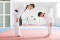 Chinese instructor and Taekwondo student bowing in exercise room — Stock Photo