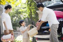 Giovane ragazzo cinese passando cestino da picnic ai genitori — Foto stock