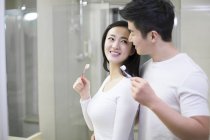Asian couple brushing teeth in bathroom — Stock Photo