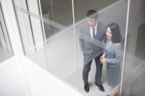 Chinese business people looking through window in office building — Stock Photo