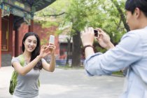 Chinese couple taking pictures with smartphones in Lama Temple — Stock Photo