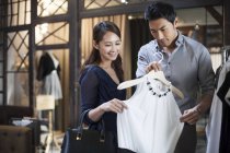 Chinese couple choosing dress in clothing store — Stock Photo