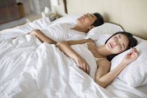 Couple chinois dormant sur le lit ensemble — Photo de stock