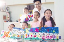 Chinese children holding paintings in art class with teacher — Stock Photo