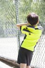 Вид ззаду хлопчика в спортивному одязі, дивлячись на дитячий майданчик — стокове фото