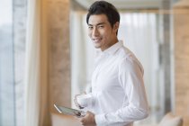Chinese man holding coffee and digital tablet — Stock Photo