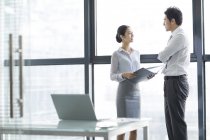 Chinesische Geschäftsfrau und Geschäftsmann reden im Büro — Stockfoto